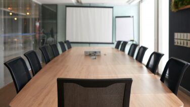 Sedia vuota in una sala riunioni executive, simbolo di una posizione di leadership vacante